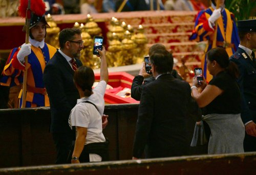 Neben dem Papst-Sarg posieren sie für Selfies