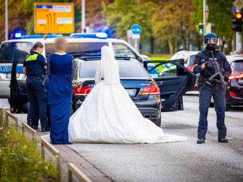 Schwerbewaffnete Polizisten durchsuchen Hochzeitskorso