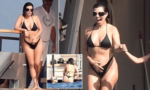 Kourtney Kardashian shows off her figure in a tiny black bikini as she enjoys a day on a $14.2million yacht with husband Travis Barker (who cheekily grabs her behind) ahead of their Portofino wedding ceremony