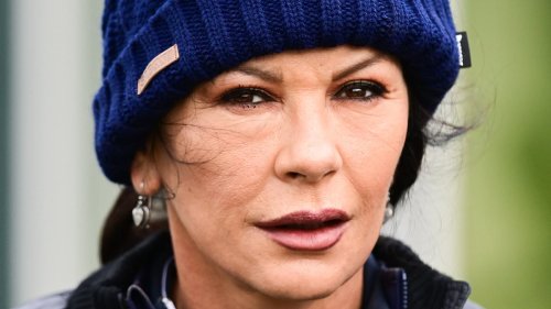 Catherine Zeta-Jones bundles up in a blue jacket and bobble hat as she takes part in celebrity golf contest in Scotland