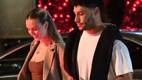 Perrie Edwards' fiancé Alex Oxlade-Chamberlain wraps an affectionate arm around her as they leave...