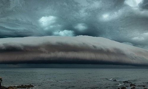 Breathtaking moment a massive 'shelf cloud' rolls across the ocean as photographer catches unique weather phenomenon off the coast of Australia