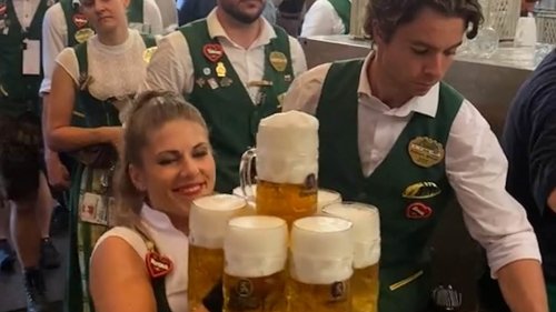 Oktoberfest waitress shows off her super-strength as she piles up 13 pints and effortlessly carries...