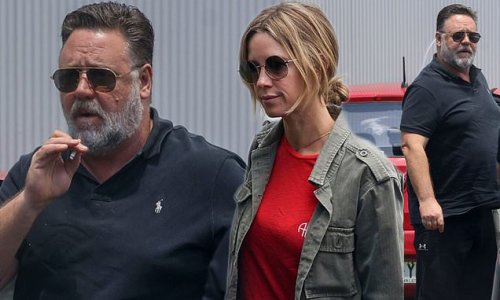 Russell Crowe puffs on a cigarette as he arrives at Sydney Airport with girlfriend Britney Theriot after promoting his Stan film Poker Face