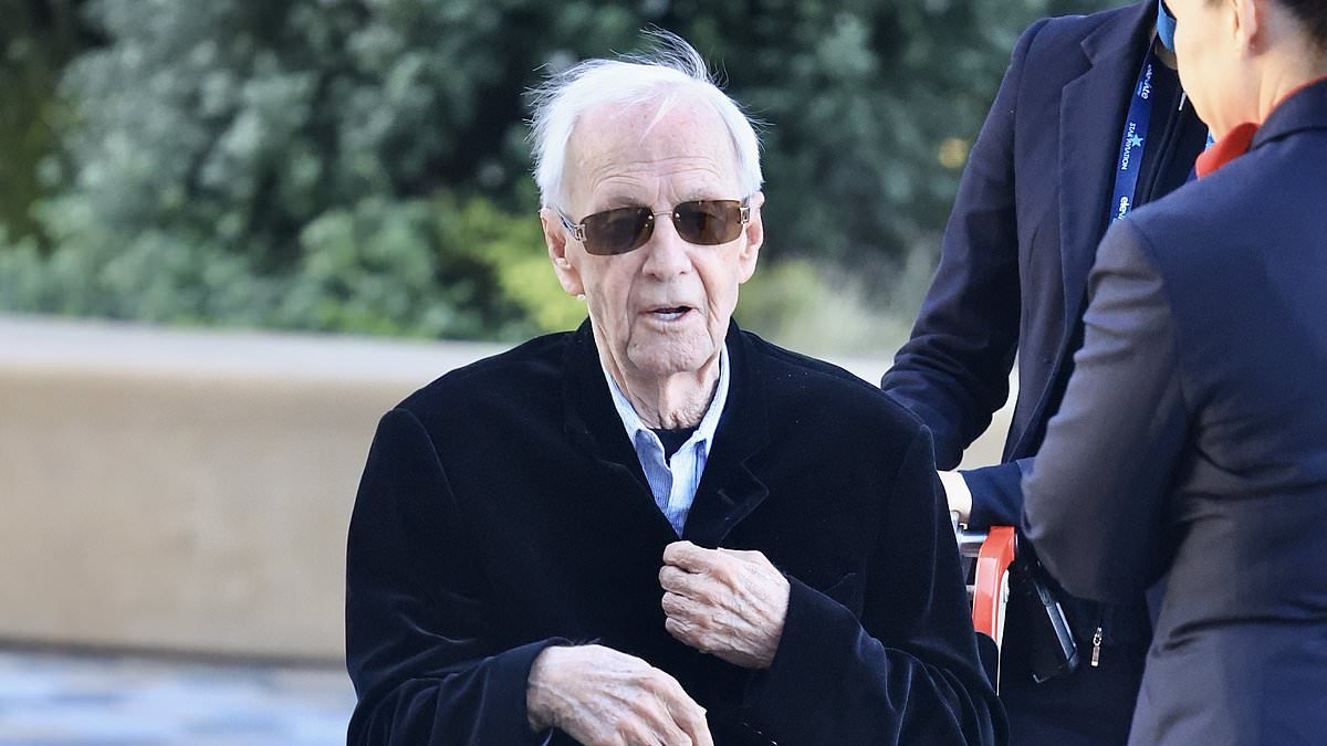 A frail Paul Hogan, 85, is pushed along in a wheelchair as he returns