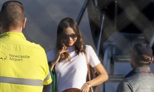Happy to be home! Beaming Miranda Kerr shows off her abs in a cropped T-shirt and baggy tracksuit pants as she lands in Australia via private jet with her husband Evan Spiegel