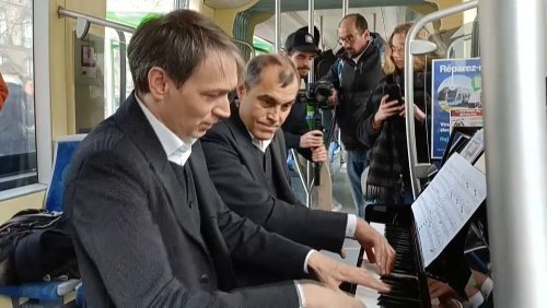 Deux musiciens installent leur piano dans un tramway pour un concert de musique classique