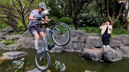 Daredevil cyclist skips across river stones in jaw-dropping stunt