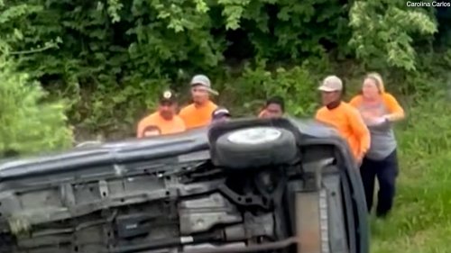 Good samaritans band together to overturn a flipped car and rescue woman trapped