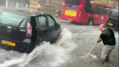 Flash floods have hit London - with one man filmed using a BROOM to try and clear shin-deep water