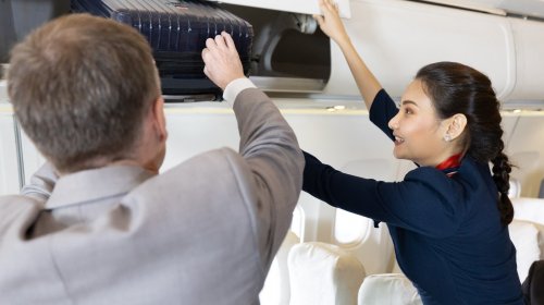 The Unexpected Reason Flight Attendants Will Never Help You Stow Your Luggage