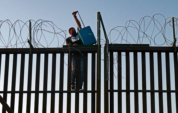 A man attempts to cross over a fence
