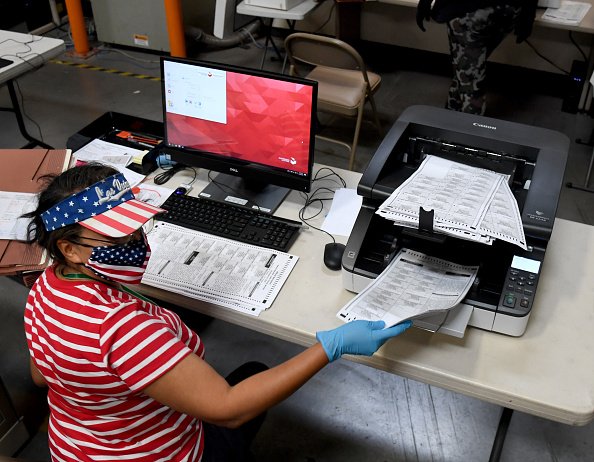 A Clark County election worker scans mail-in ballots at the Clark...