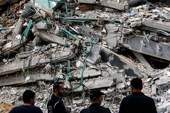 Palestinesi davanti a una torre distrutta dopo il cessate il fuoco a Gaza