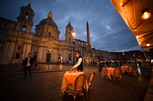 An employee cleans up a table on an empty terrace at Piazza Navona