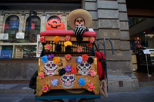 An organ grinder with his face painted as skull as part of...