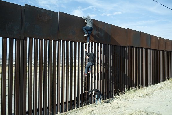Men scaling border wall