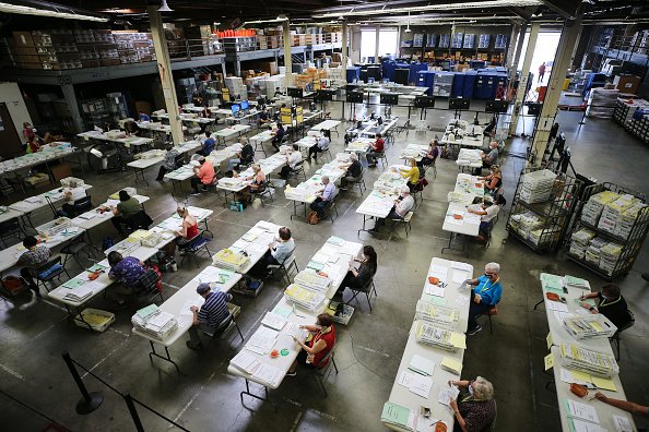 Election workers process mail-in ballots at the Orange County...