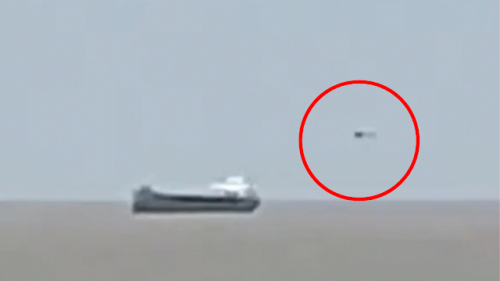 Silver UFO Can Be Seen Stalking Behind A Cargo Ship