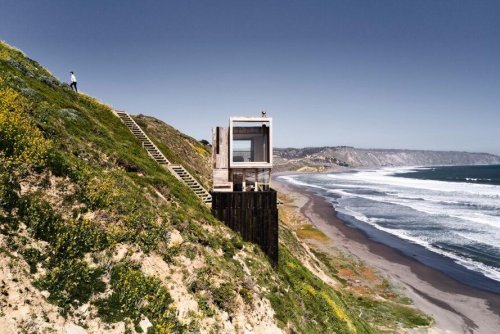 Two holiday cabins on stilts sit lightly by the ocean