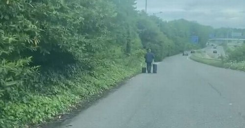 Incredible footage captures man walking down main road with suitcases near Manchester Airport