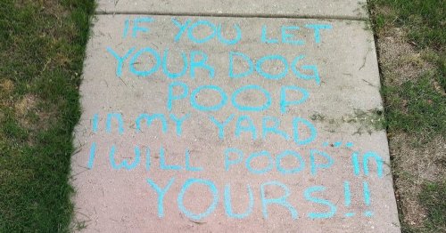 Threatening message to dog owners written in chalk on pavement