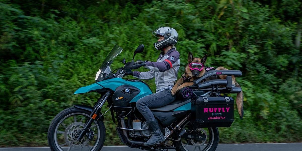 Woman Biking Globe With Dog on Back of Motorcycle thumbnail