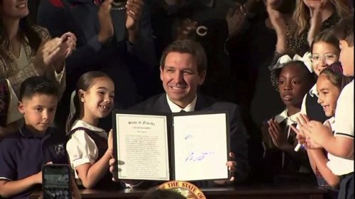 Flanked by children, Gov. DeSantis (R-FL) signs a bill to remove income eligibility requirements for school vouchers.