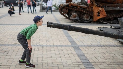 Boy stares down barrel of smashed Russian tank and kids pose with toy guns in a poignant show of Ukrainian resistance