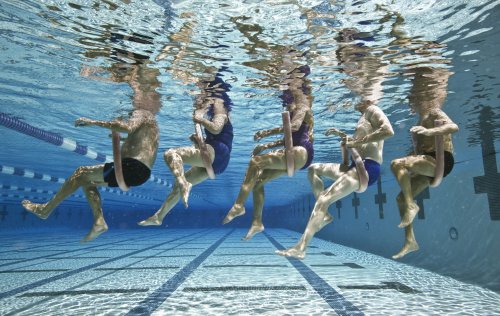 Five senior people in swimming pool, underwater, low section