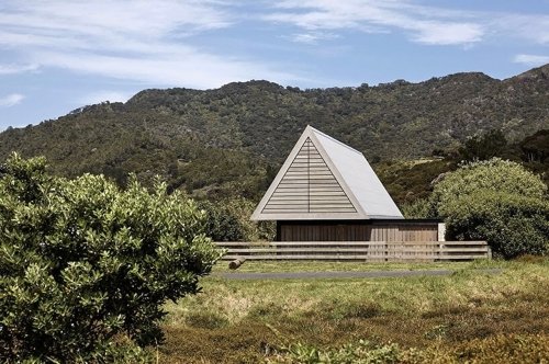 This off-grid A-frame cabin in New Zealand is inspired by traditional Maori huts and the local coastal landscape